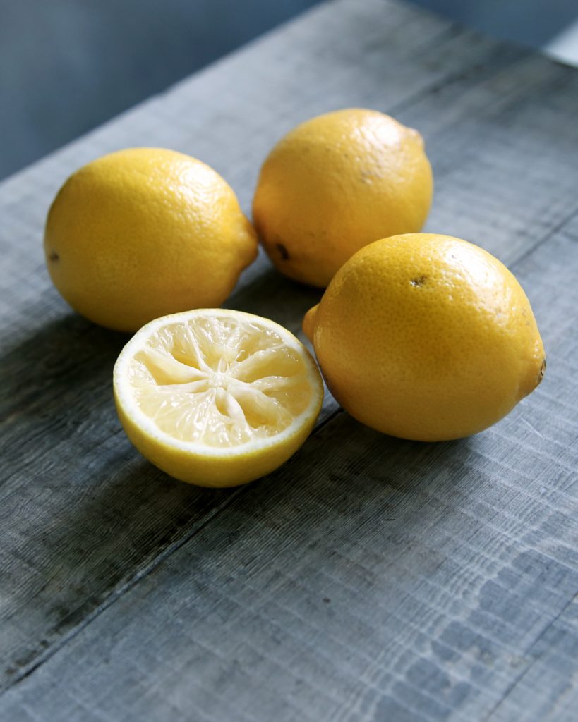 Trois citrons entiers et un demi-citron sur une table en bois