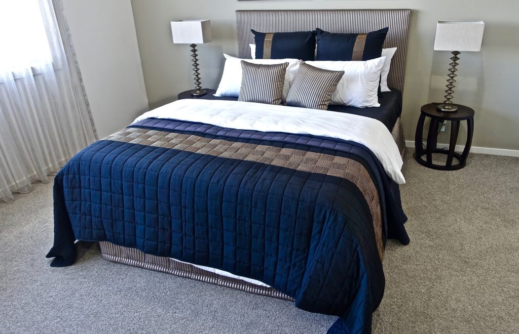 lit double avec deux tables de chevet symétriques, couvre-lit bleu marine et beige