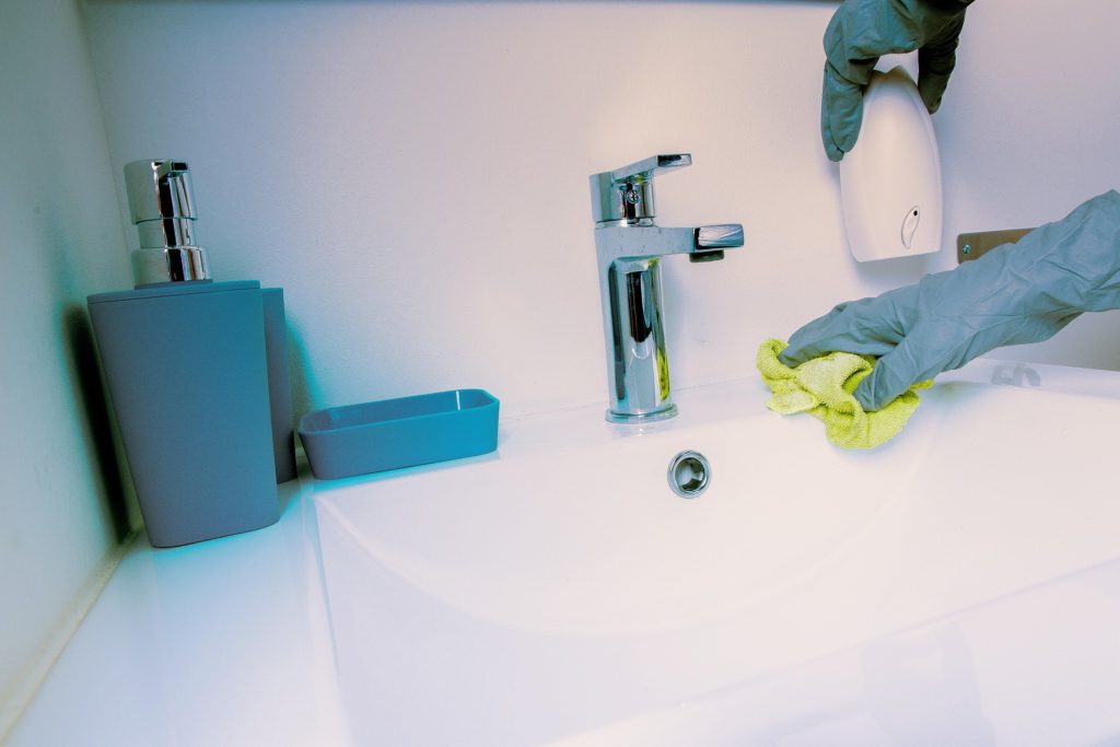 Une personne avec des gants en caoutchouc nettoie un lavabo